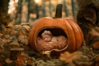 newborn baby nestled in a pumpkin prop with a fantasy forest halloween backdrop in autumn colors for digital photography