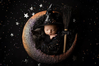 newborn baby in gothic halloween setup with witches broom and twinkle lights, perfect for face swap photography