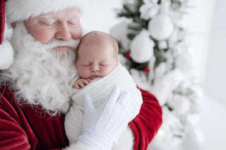 newborn in santa claus suit on a christmas themed digital backdrop with snowflakes