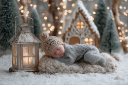 newborn baby in festive christmas scene with gingerbread house and lantern